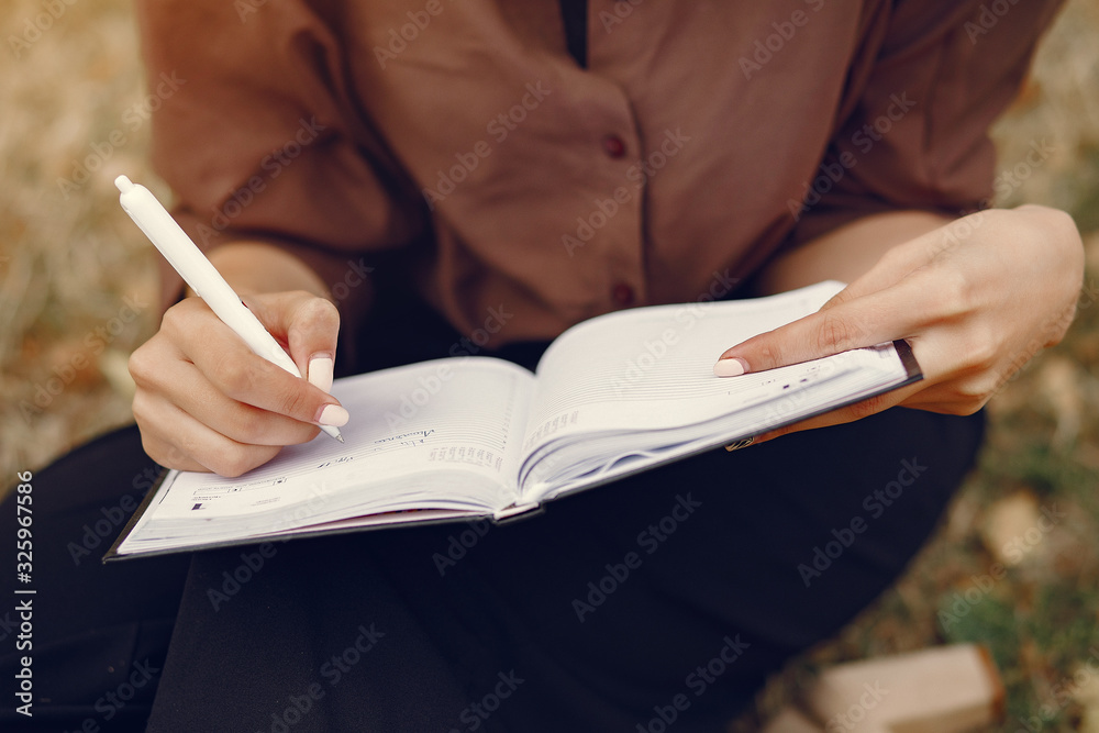 Beautiful girl studies. Student use the notebook. Lady in a summer park Beautiful girl studies. Student use the notebook. Lady in a summer park