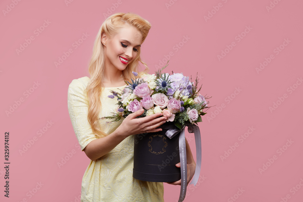 Pretty girl in retro clothes with bouquet of rose flowers in hat box on pink studio background. 8 march. Birthday party. Pretty girl in retro clothes with bouquet of rose flowers in hat box on pink studio background. 8 march. Birthday party.