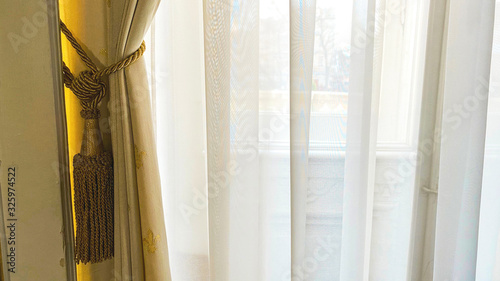 Curtain with warm sunlight close-up with decorative elements.