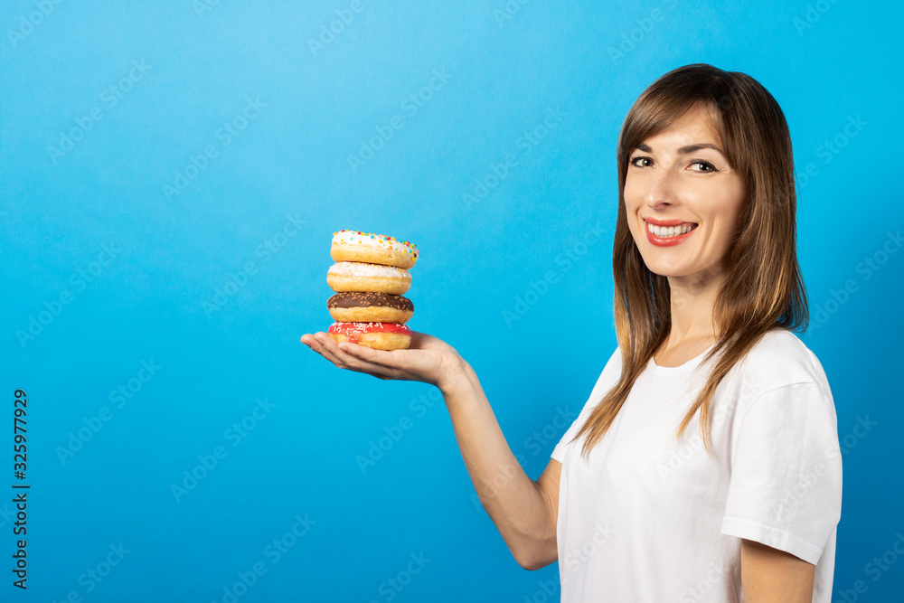 young girl holds four donuts on a palm on a blue background. Banner. The concept of diet, bright colors, emotions young girl holds four donuts on a palm on a blue background. Banner. The concept of diet, bright colors, emotions