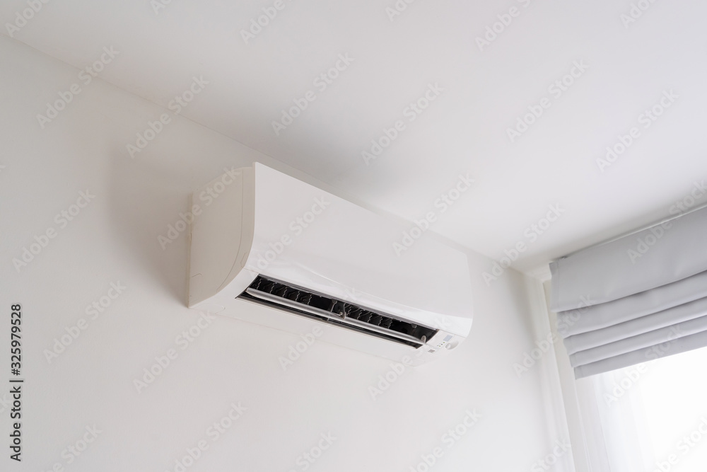 Air conditioner on white concrete wall in room space. Air conditioner on white concrete wall in room space.