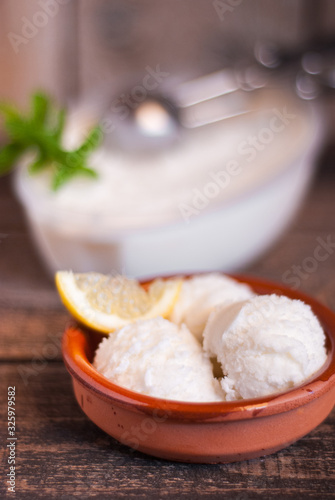 Clay dish with homemade lemon ice cream on a dark wooden table