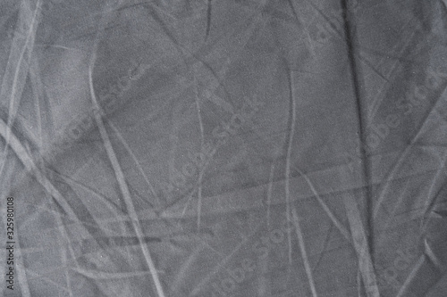 Abstract pattern of a gray crumpled bed sheet in bedroom. Gray wrinkled fabric texture rippled surface, Close up bed sheet in the bedroom.