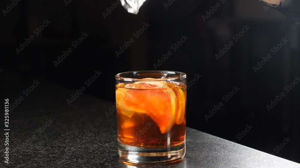 At a night club. Cocktail making concept. Ice being dropped into glass with alcohol in slow motion. 180fps. Close-Up, Isolated black Background. Falling ice cubes on bar counter. Full hd video At a night club. Cocktail making concept. Ice being dropped into glass with alcohol in slow motion. 180fps. Close-Up, Isolated black Background. Falling ice cubes on bar counter. Full hd video