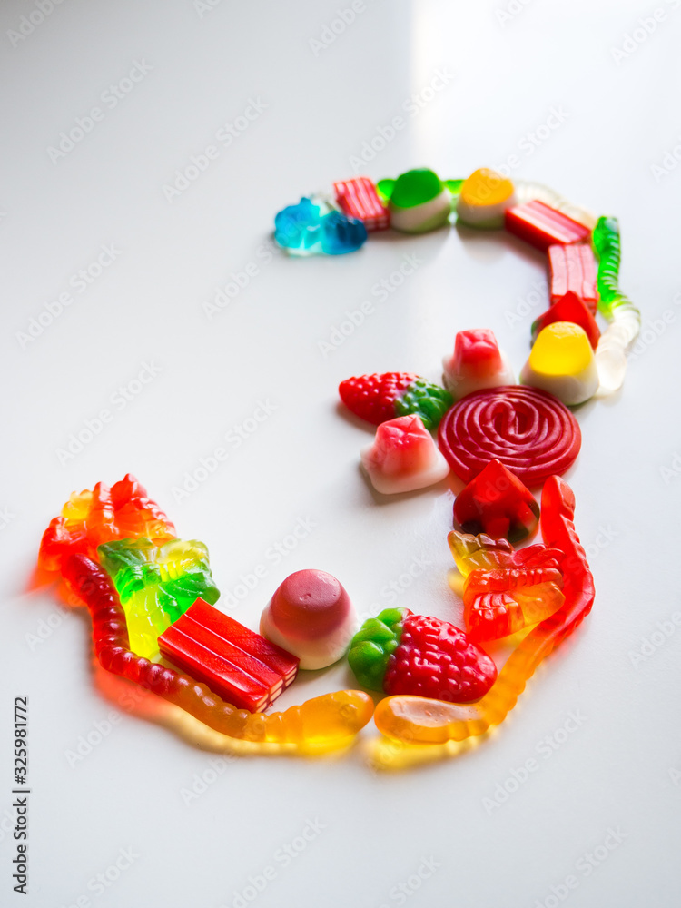 Number three made up of sweets on a white table