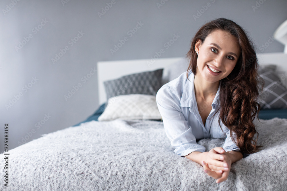 Portrait of beautiful young brunette woman with attractive smile in bed at home. Portrait of beautiful young brunette woman with attractive smile in bed at home.
