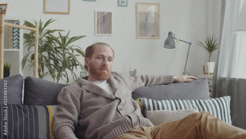 Lockdown of Caucasian middle-aged man wearing casual clothes sitting on sofa, playing movie on TV and relaxing Lockdown of Caucasian middle-aged man wearing casual clothes sitting on sofa, playing movie on TV and relaxing
