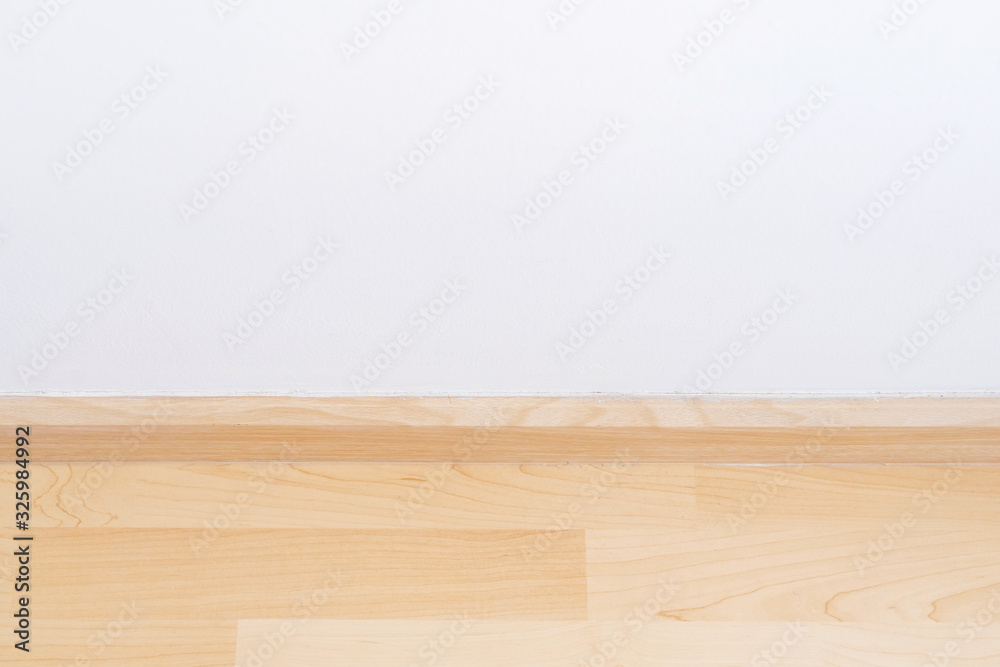 Wooden wall base skirting, finishing material with wood laminate floor and white mortar wall. Empty room with white wall and wooden floor. Wooden wall base skirting, finishing material with wood laminate floor and white mortar wall. Empty room with white wall and wooden floor.