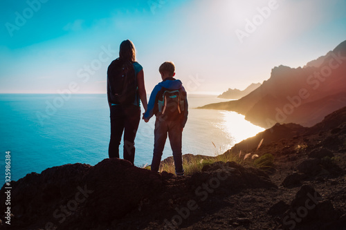 silhouette of mother and son travel at sunset mountains near sea
