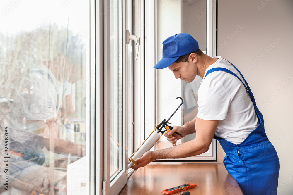Male worker installing window in flat Male worker installing window in flat