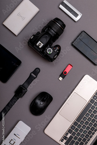 Flat lay of designer workplace. Top view work space photographer with digital camera, smartwatch, memory card, external harddisk, USB card reader and accessory on grey background with copy space.