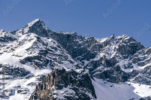 The snowy mountains of Valsesia seen from the val d'otro, during a sunny day near the town of Alagna, Italy - February 2020.