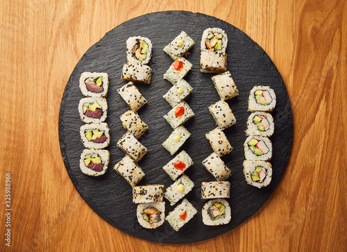 Various kinds of sushi roll set served on black stone. Japanese food