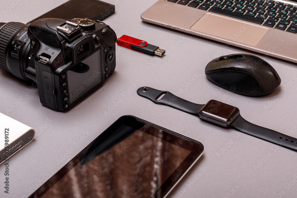 Digital camera, usb with external harddisk or battery and equipment of the professional photographer on grey paper background. Designer workplace concept. Digital camera, usb with external harddisk or battery and equipment of the professional photographer on grey paper background. Designer workplace concept.