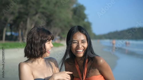 Holiday concept. Two beautiful girls in bikinis are fun pointing at the beach. 4k Resolution. photo