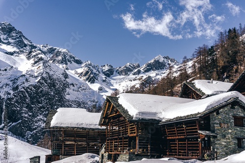 The traditional architecture of the Walser villages in the valleys of Monte Rosa, during a fantastic winter day, near the town of Alagna, Italy - February 2020. photo