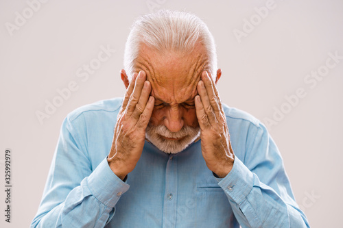 Portrait of senior man who is having headache.