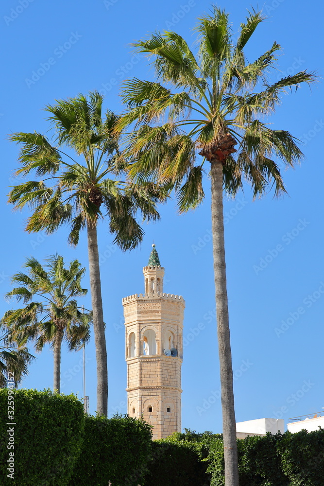 Close-up on the minaret of Soliman Hamza mosque surrounded by palm trees in the city of Mahdia, Tunisia