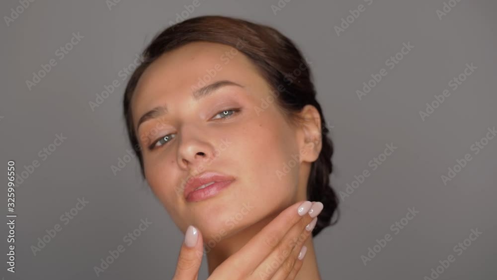 beauty, bodycare and people concept - beautiful young woman touching her face over grey background beauty, bodycare and people concept - beautiful young woman touching her face over grey background