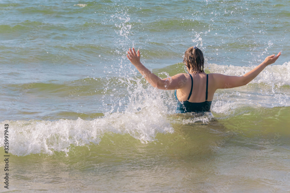 Fototapeta premium Woman doing splashes of water in waving sea
