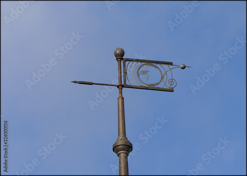 Old iron weather vane on the roof of the house