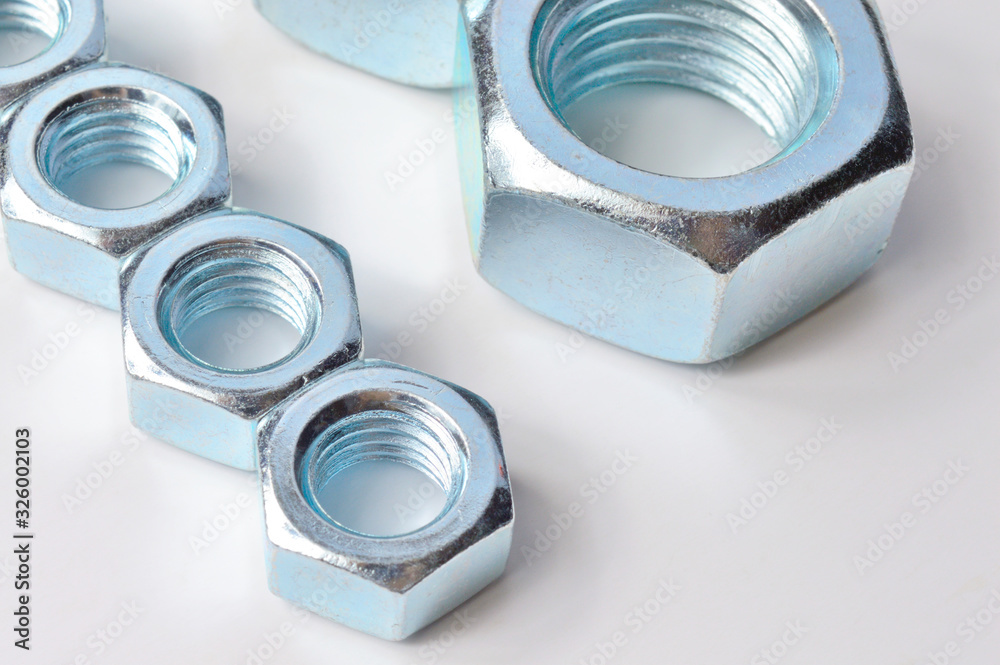 New, chrome new nuts of different sizes on a white background.