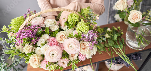 Fototapeta Naklejka Na Ścianę i Meble -  Education in the school of floristry. Master class on making bouquets. Summer bouquet in a wicker basket.. Learning flower arranging, making beautiful bouquets with your own hands. Flowers delivery