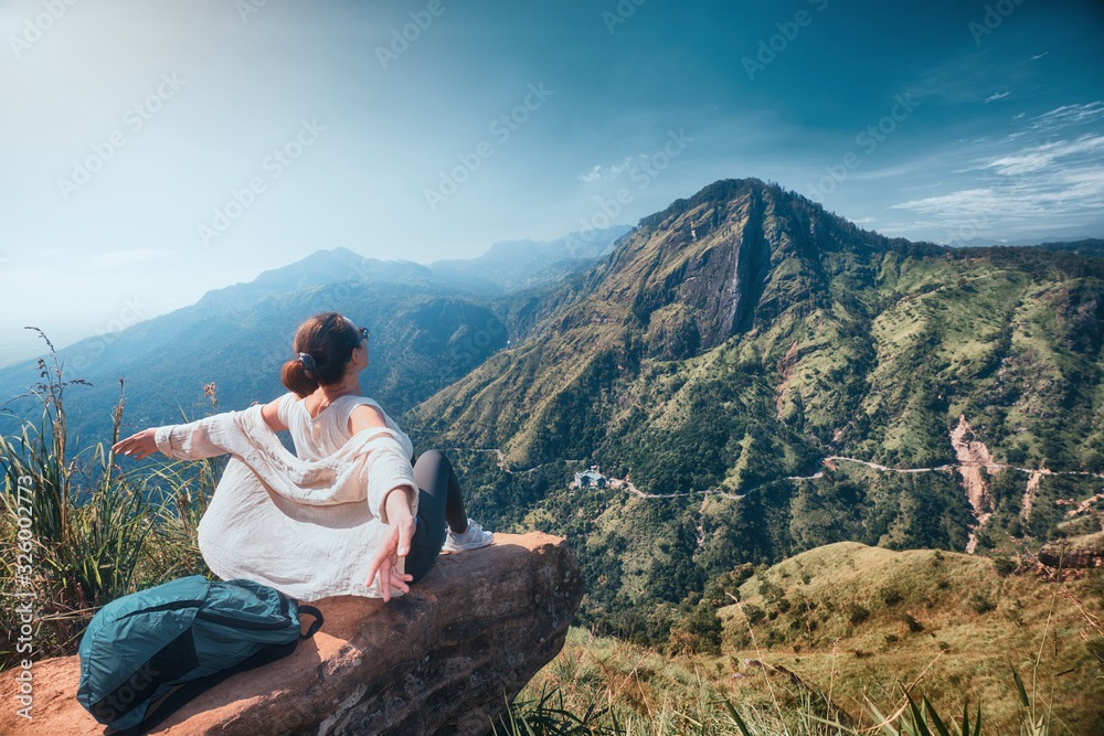 Woman traveler enjoying early morning beautiful nature on background of mountain peak 