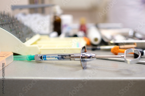 Table with stomatological equipment and dental tools in stomatology office. Focus on dental anesthesia injection syringe. Concept of dentistry, medicine and health care.