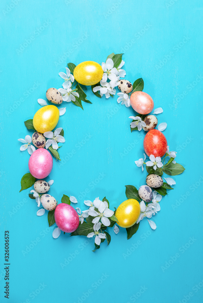 Colored hen eggs, quail eggs and white Apple tree flowers laid out as Easter egg on turquoise painted wooden background.