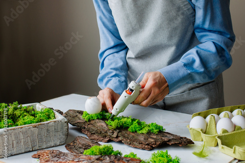 Woman working with glue gun preparing Easter decoration photo