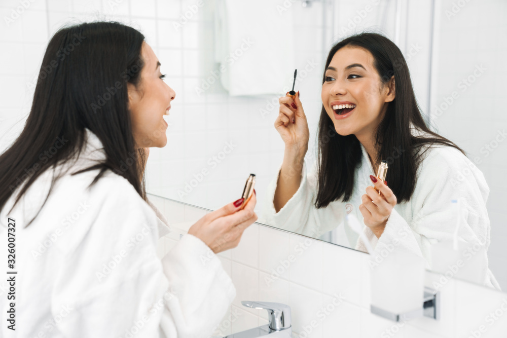 Woman indoors at home in bathroom apply makeup. Woman indoors at home in bathroom apply makeup.