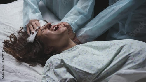 exhausted tired woman in labor gives birth to child, maternity ward pushing hard, young mother screams writhing in pain during childbirth in hospital, professional medical care of doctors, pregnancy photo