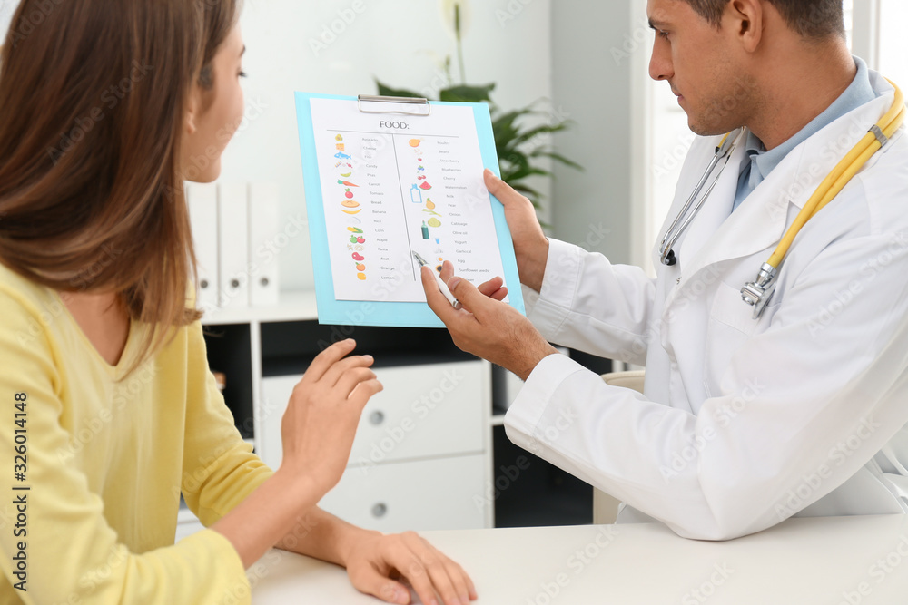 Nutritionist consulting patient at table in clinic Nutritionist consulting patient at table in clinic