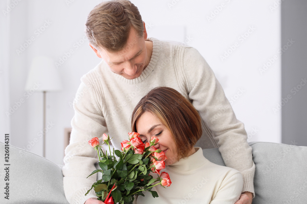 Happy husband giving his wife bouquet of flowers at home Happy husband giving his wife bouquet of flowers at home