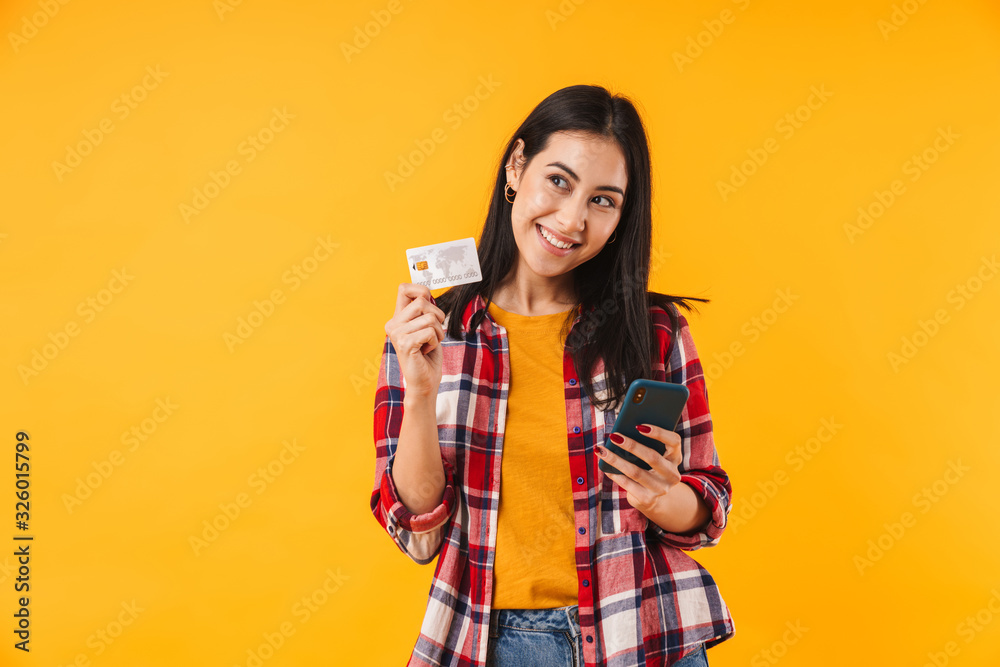 Image of happy attractive woman holding credit card and using cellphone Image of happy attractive woman holding credit card and using cellphone