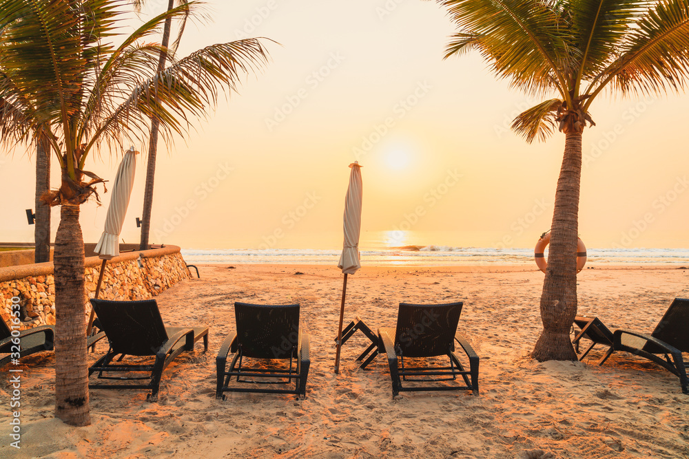 Obraz premium umbrella chair beach with palm tree and sea beach at sunrise times