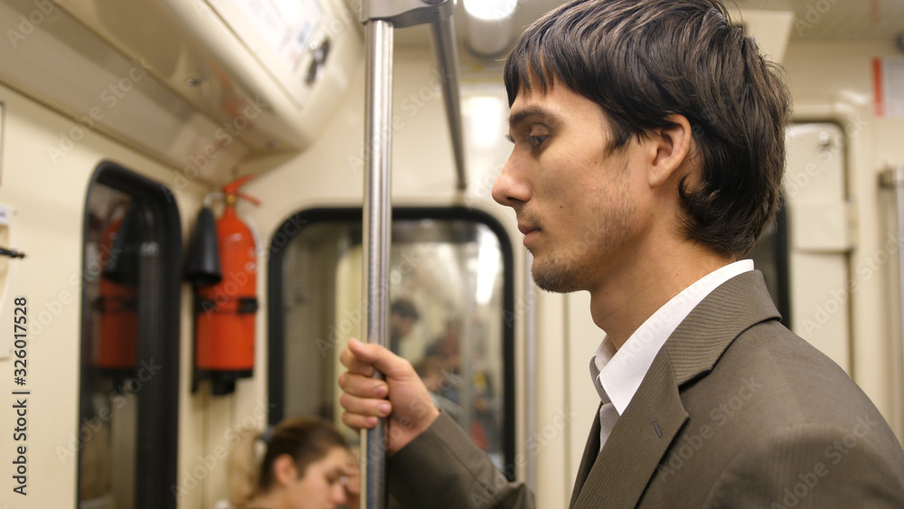 Young handsome businessman in suit standing in the subway on the way home from work Young handsome businessman in suit standing in the subway on the way home from work
