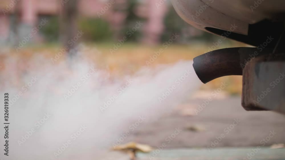 Tail pipe of old car from which cloud of exhaust comes out. Air