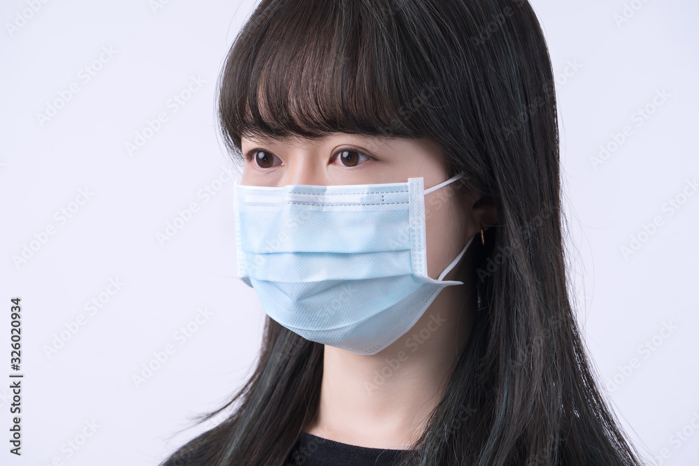 Young Asian woman portrait, wearing a medical surgical blue face mask for epidemic prevention, air pollution isolated on white background, copy space, close up, cut out Young Asian woman portrait, wearing a medical surgical blue face mask for epidemic prevention, air pollution isolated on white background, copy space, close up, cut out