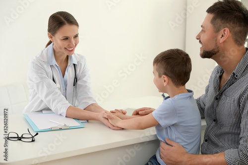 Father and son visiting pediatrician. Doctor working with patient in hospital