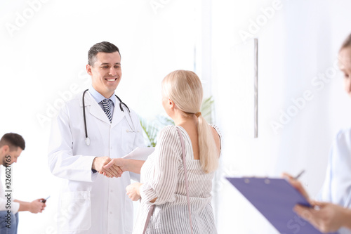 Doctor and patient shaking hands in hospital hall