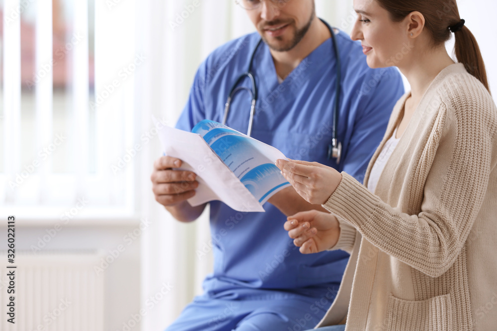 Fototapeta premium Doctor showing medical record to patient in clinic, closeup
