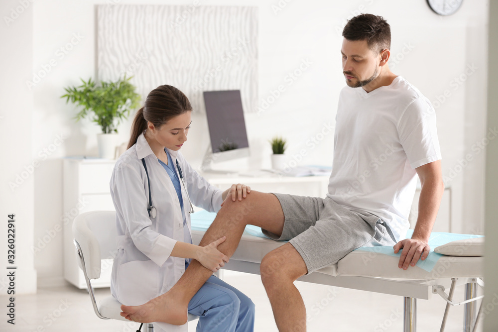 Obraz premium Female orthopedist examining patient's leg in clinic