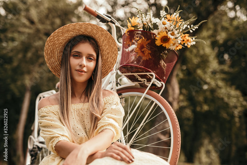 Stylish young woman sitting near bike