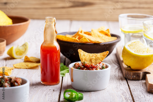 Konstfotografi Two bowls full of salsa dip, hot red chili sauce bottle and tortilla chips
