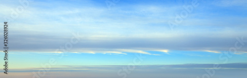  Light blue spring sky background with long striped clouds on the horizon.