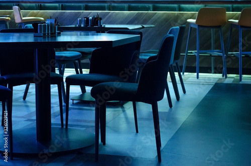 Tables and upholstered chairs in a cafe in subdued dark intimate blue light