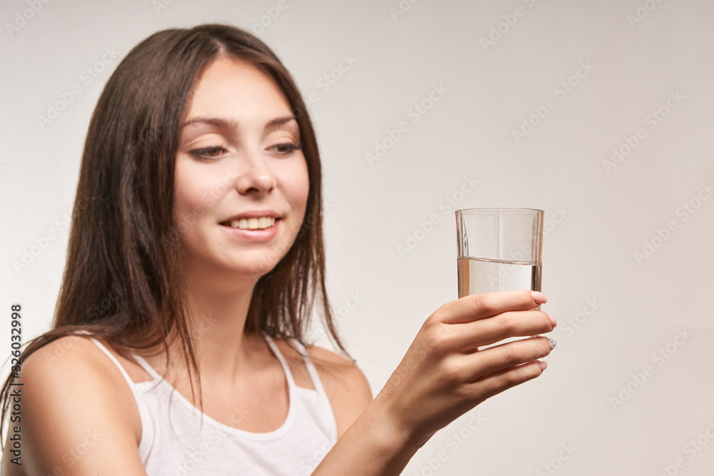 Young beatiful girl hold water glass. Hydrate female face. Happy women indoors. Morning routine. Pretty portrait. Young beatiful girl hold water glass. Hydrate female face. Happy women indoors. Morning routine. Pretty portrait.