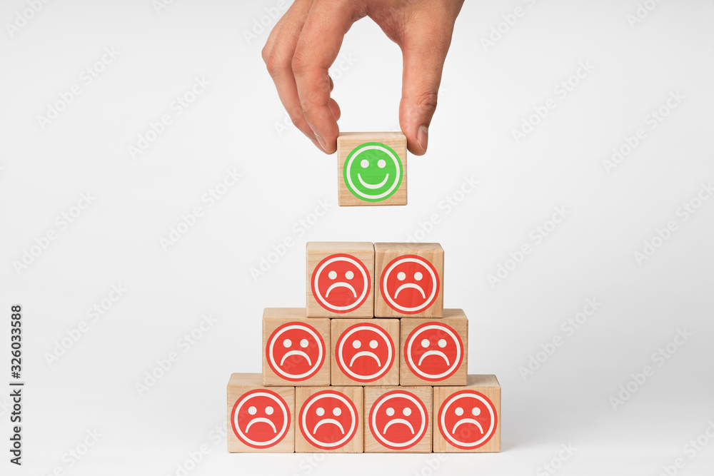 Hand holding wooden cube with face emotion. Concept of customer service experience and business satisfaction survey. Hand holding wooden cube with face emotion. Concept of customer service experience and business satisfaction survey.
